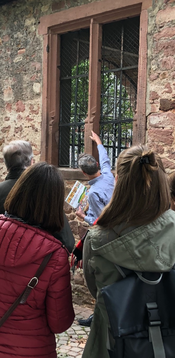 Bild einer Gruppe von Menschen, die vor einer Kirche steht und einem Stadtführer aufmerksam zuhört.